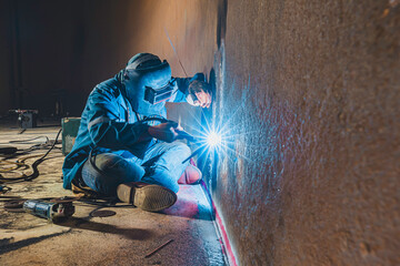 Welders at work in metal argon industry, welding metal plate tank construction close up wear protective gloves and mask in side confined