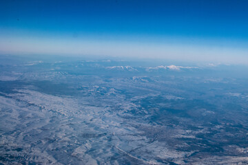 Fototapeta premium view of mountains covered with snow from an airplane window, Cyprus