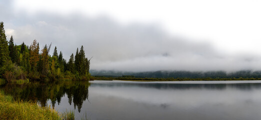 Fototapeta premium Early misty morning at autumn colored lake with cloudy sky fading to transparent. Vermillion Lake Banff 