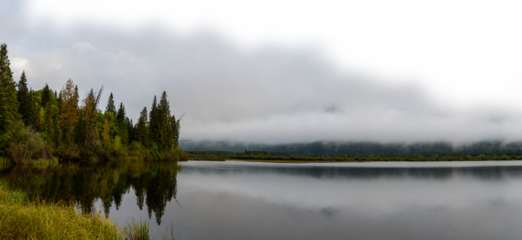 Early misty morning at autumn colored lake with cloudy sky fading to transparent. Vermillion Lake Banff
