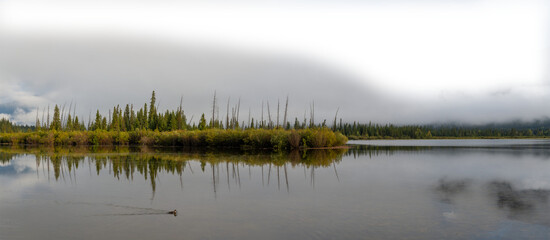 Early misty morning at autumn colored lake with cloudy sky fading to transparent. Vermillion Lake Banff
