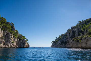 Looking from the beach to the horizon of the sea between the rocks of the parc of the calanques near Marseille and Cassis with light blue water on a sunny day.