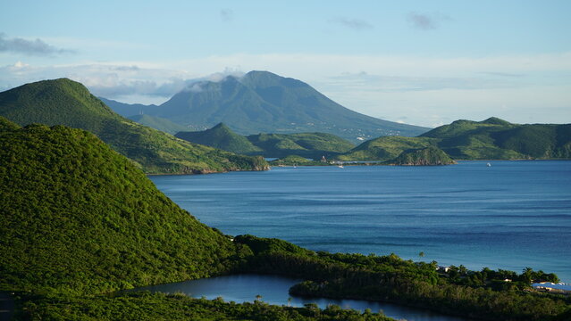 Landscape photo of the Caribbean Island of Saint Kitts & Nevis in the West Indies with view of blue water and lush green forest covered mountains. 