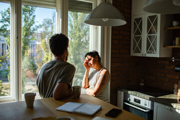 Thoughtful couple having a serious conversation at home by the window