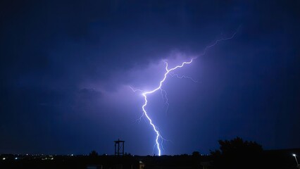 Dramatic lightning strikes illuminate the night sky during a storm near a city skyline