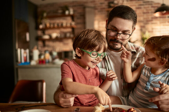 Father enjoying breakfast time with two young sons in cozy kitchen