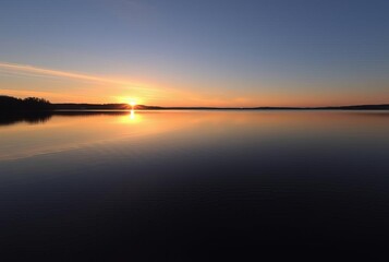 Obraz premium Lake Sunset A tranquil sunset reflected in the calm waters of a