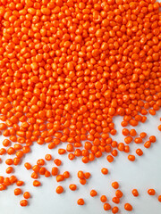 Orange taffy masterbatch granules on white background,color pigment carrier polymer in plastic industry,suitable for plastic company catalogue