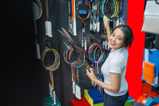 female sport store staff putting recket in display