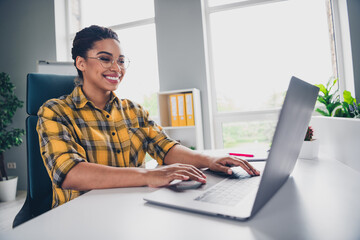 Photo of lovely young lady working netbook dressed yellow plaid shirt comfortable startup office loft room interior