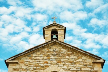 Fototapeta premium A medieval-style bell tower with a large cross on top in a quiet town or village setting