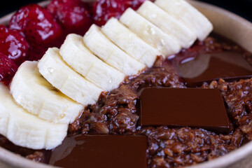 Healthy breakfast with whole oats, oat milk, chia seeds, cocoa, strawberries, honey, banana, and dark chocolate