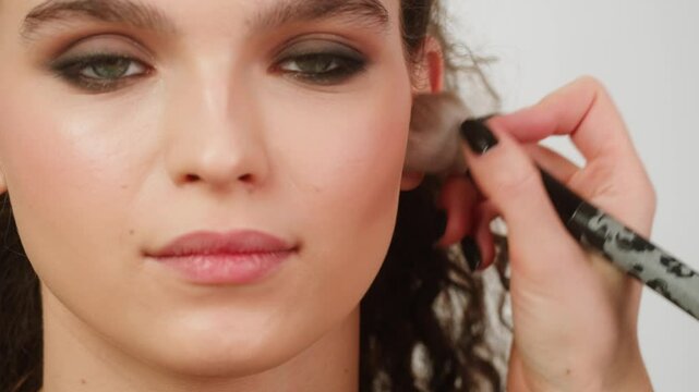 Eye shadow makeup to the upper eyelid, close-up. Makeup artist applies a bright eye shadow with a make-up brush.Tutorial master class of professional makeup, smoky eyes 