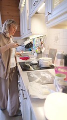 Happy attractive young woman housewife preparing breakfast for family. Mom stands near the kitchen stove and prepares dinner