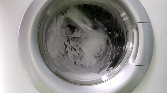 Close-up of clothes washing in a machine with foam. Concept of laundry, cleanliness, and modern household chores in daily life.