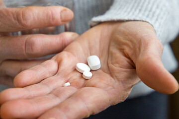 An old woman holds pills in her hands. Close up view.