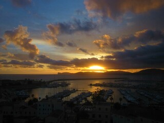 Sun setting through the clouds over the harbour in Sardinia
