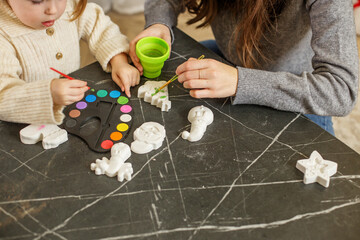 Naklejka premium Child painting Christmas decorations at home with parent during holiday season