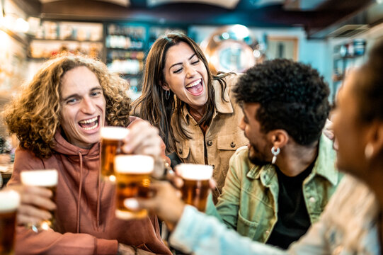 Group of happy people drinking and toasting beer at brewery bar restaurant - Happy friends enjoying happy hour sitting at vintage pub table - Friendship concept with young people having fun together