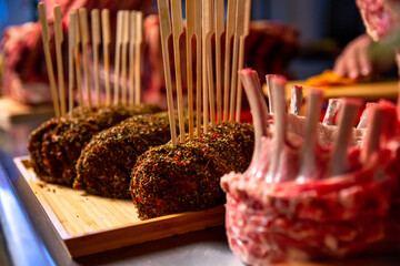 Close up of roll seasoned with herbs and kitchen sticks on a wooden cutting board. Barbecue preps seasoned with pepper mix. Cooking conept.