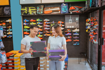 asian athletic footwear sellers holding shoe box and checking product
