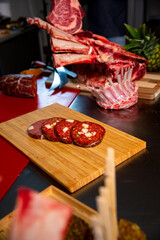 Slices of homemade sausageon a wooden table in a butcher shop along with beef. Butchers table with sausage and ribs.
