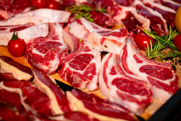 Lamb ribs steak surrounded by diffferent meat handmade products. Shot of butchery manufactory table with meat goods.