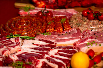 Set of raw lamb ribs and barbecue skewers decorated with rosemery and tomatoes. Meat products on display on the table.