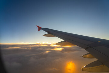 Fototapeta premium Wing of an aircraft against a vibrant sunset over clouds during a serene evening flight