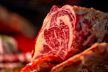 Close up ribeye steak on a wooden table in a butcher shop. Juicy fresh meat steak on board with different meat goods around.