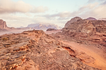 Red sandstone rocks formations in Wadi Rum (also known as Valley of the Moon) desert, Jordan. Two small people at distance for scale
