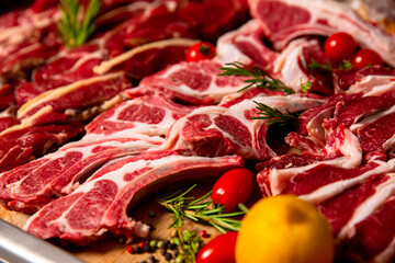 Fresh raw lamb carcass ready for sale on display on a wooden table in a butcher shop with other meat products. Displayed raw lamb body for sale.