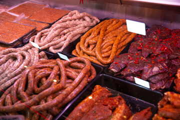 Diverse range of sausages and meat prepared to be cooked in a butcher shop. Seasoned meat with spices for barbecue.