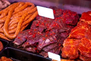 Close up raw meat sausages on the supermarket shelves assortment on showcase in a butcher shop. Selection of homemade sausages for sale.