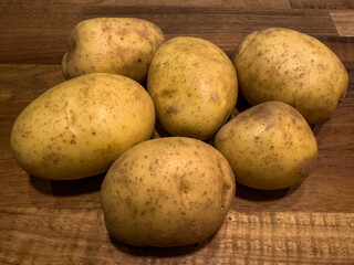 Close up brown dirty potatoes on a wooden background. 