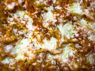 Close up tomato tuna pasta bake with melted grated cheese. 