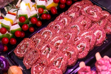 Tomatoes, cucumbers and cheese and row beef roll for grill or barbeque. Food industry meat for sale.