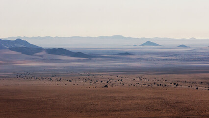 View over the vast and empty plains of the Spergebiet in the Namib Desert with the distant bleu inselbergs,