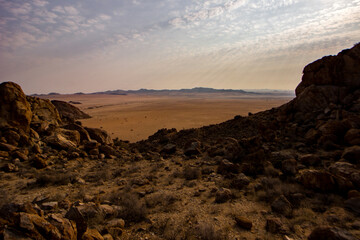 Late afternoon sunbeams, shining through high altitude clouds, over the vast empty plains of the Sperrgebiet in Namibia