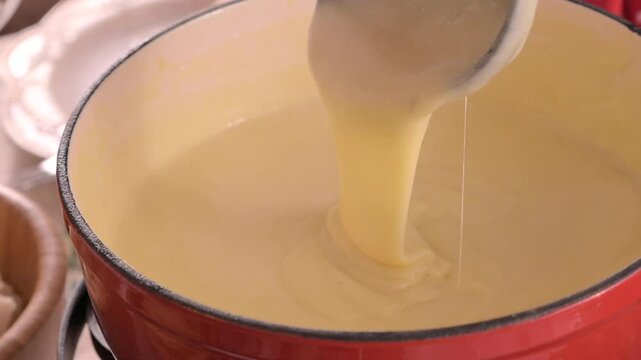 Cozy Swiss fondue setup with melted cheese, bread, pickles, and wine on a rustic table. advertising, social media campaigns, or food-related promotions. High quality 4k footage