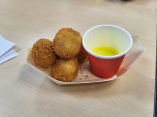 A close-up photo of a wooden bowl filled with crispy bitterballen, served with a red cup of mustard. The perfect snack!