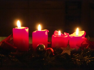 Zum vierten Advent brennen vier rote Kerzen auf einem Adventsgesteck