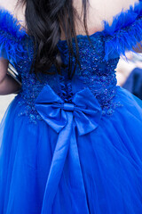 Close-up of a woman wearing a formal  blue dress, her hands with an attractive manicure, holding a glittering handbag. Selective focus.