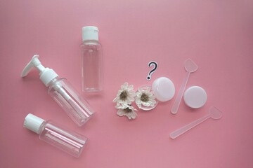 Cosmetic travel kit on pink background, top view. Minimalist body care beauty products for vacation or journey. travel size transparent cosmetic bottles.