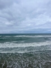 Cloudy seascape, seashore waves, natural sea horizon, cloudy sky