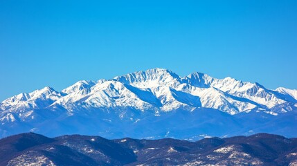 Obraz premium Majestic Snow-Capped Mountains Under a Clear Blue Sky in Winter: A Breathtaking View of Nature's Splendor and Alpine Beauty