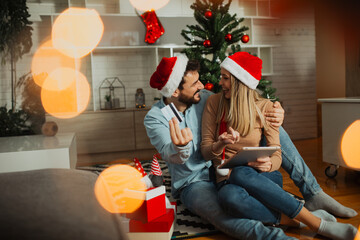 Sweet couple using tablet for buying at Christmas time