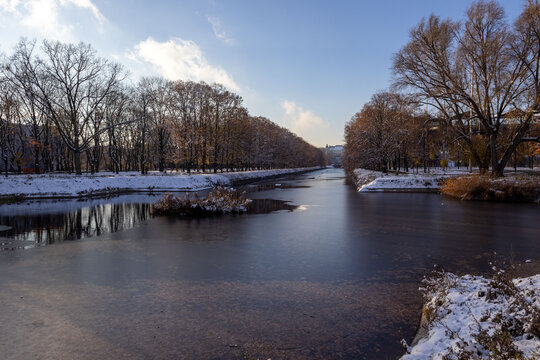 Warsaw city park with a canal, Ujazdowski Castle in the distance, first day of snowfall