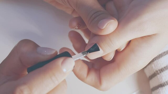 Manicurist painting her client's nails. Professional manicurist applying white nail polish to young girl's nails.
