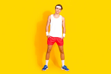 Energetic young man in activewear standing confidently on vibrant yellow background